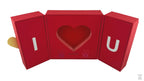 A red folding gift box with a heart cut-out design on the lid and a chain and pendant illustration.