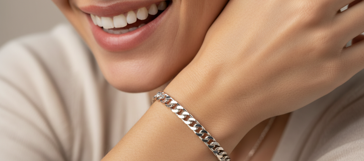 Close-up of a person wearing a silver bracelet on a neutral background